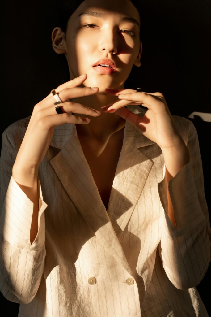 A fashionable woman elegantly posing in sunlight with expressive hands.